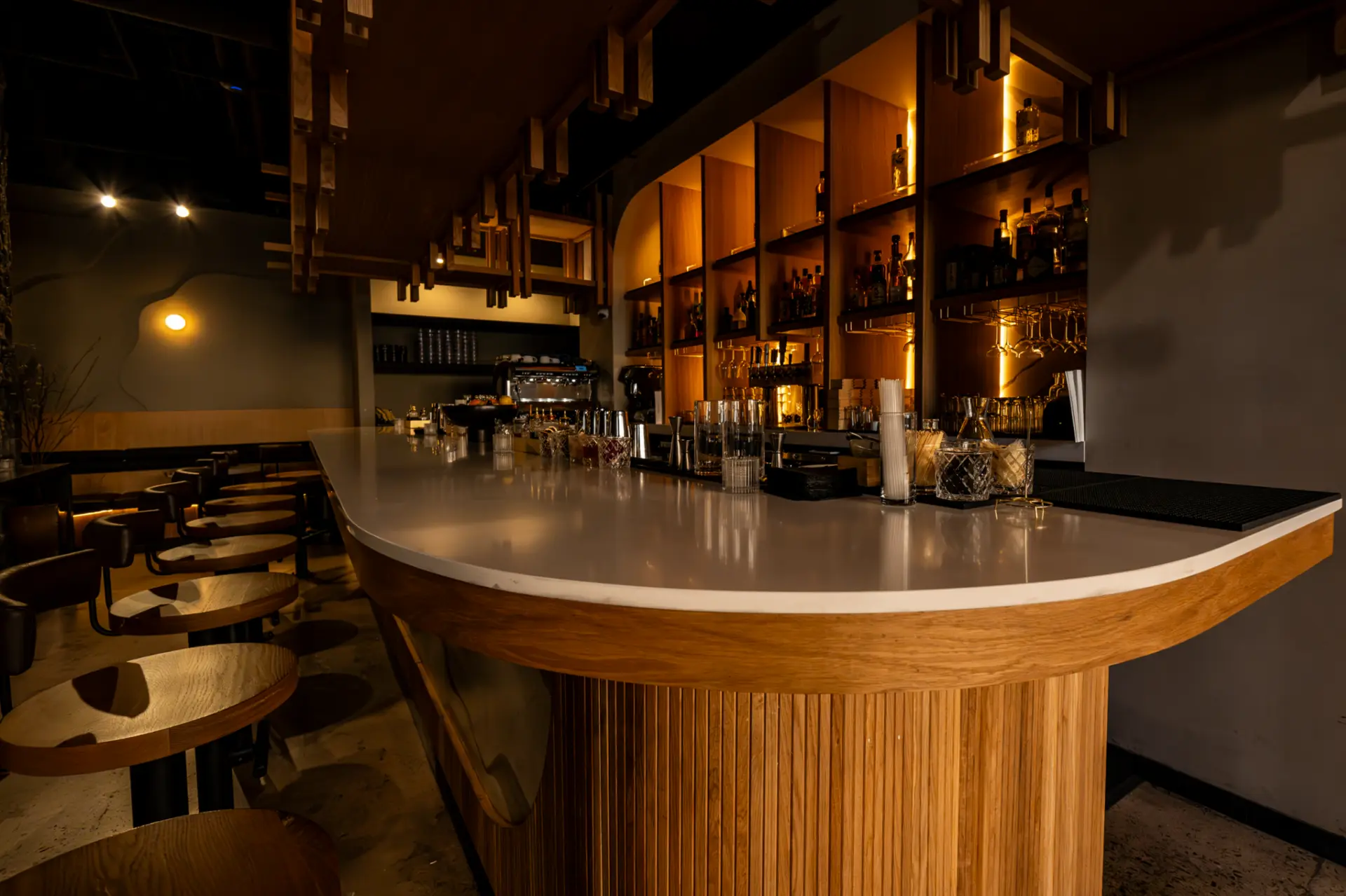 Curved white stone bar top on a fluted wood base in a dimly lit restaurant bar