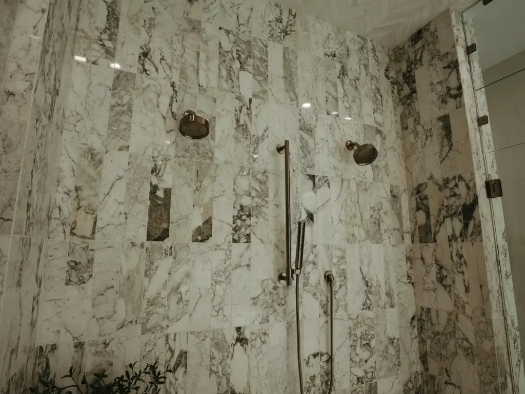 Dual-head walk-in shower with heavily veined marble walls