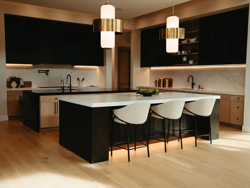 Kitchen with a black stone waterfall island, white bar stools, marble backsplash and brass pendants