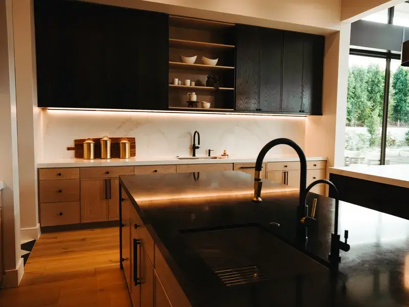 Black stone kitchen island with an integrated sink and a marble backsplash behind it