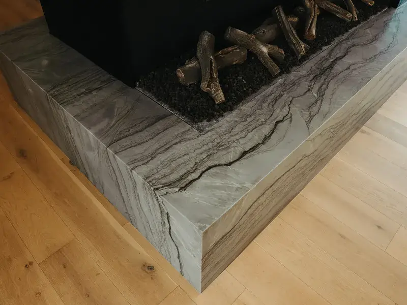 Close-up of a quartzite fireplace surround with a waterfall edge and dramatic gray veining