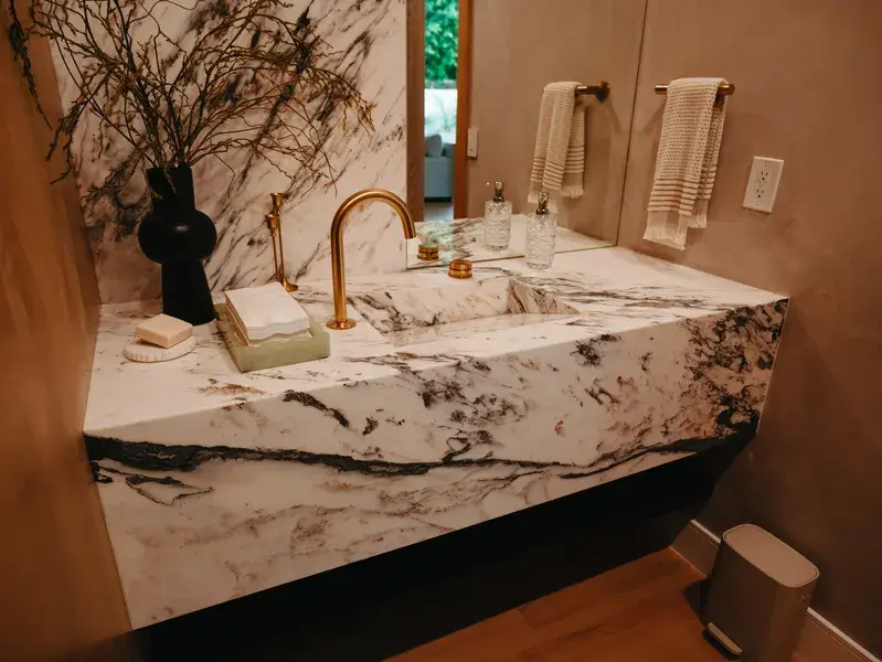 Marble waterfall floating vanity with an integrated sink and a gold faucet
