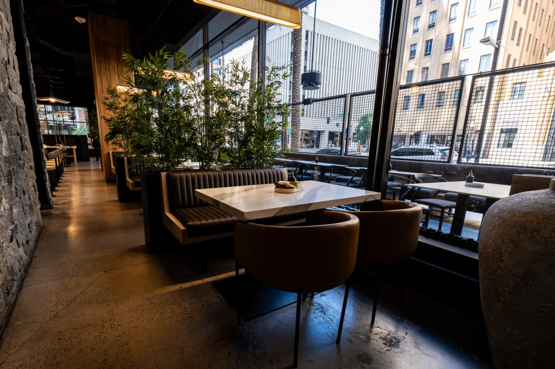 Restaurant dining room with marble-top tables beside tall windows